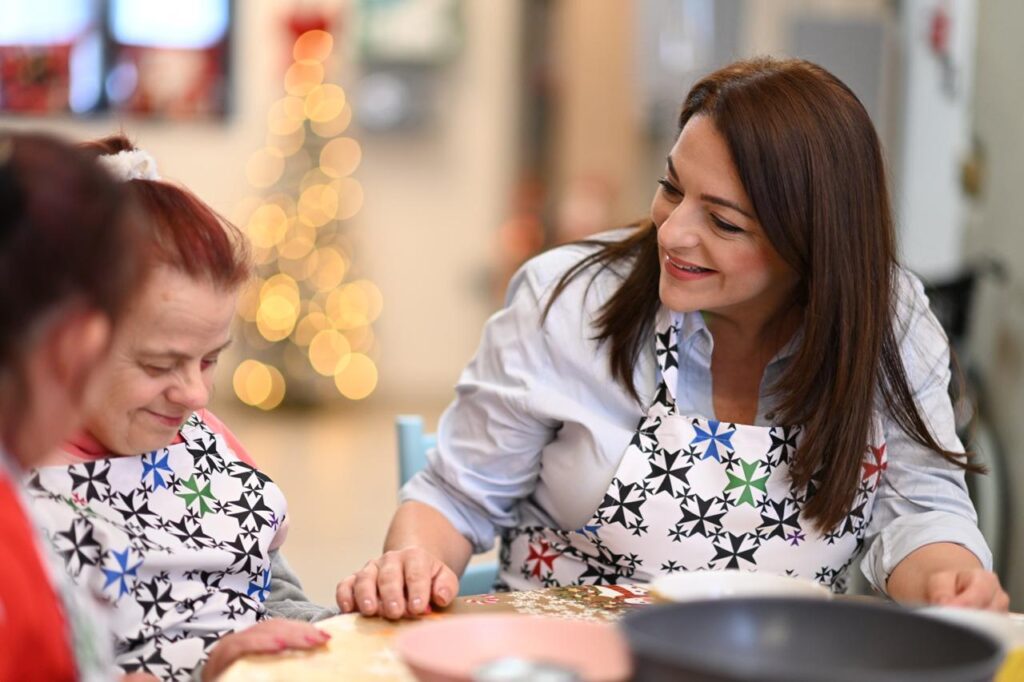 Il-Ministru Julia Farrugia bilqeda mal-mejda ma' żewġ persuni b'diżabilità