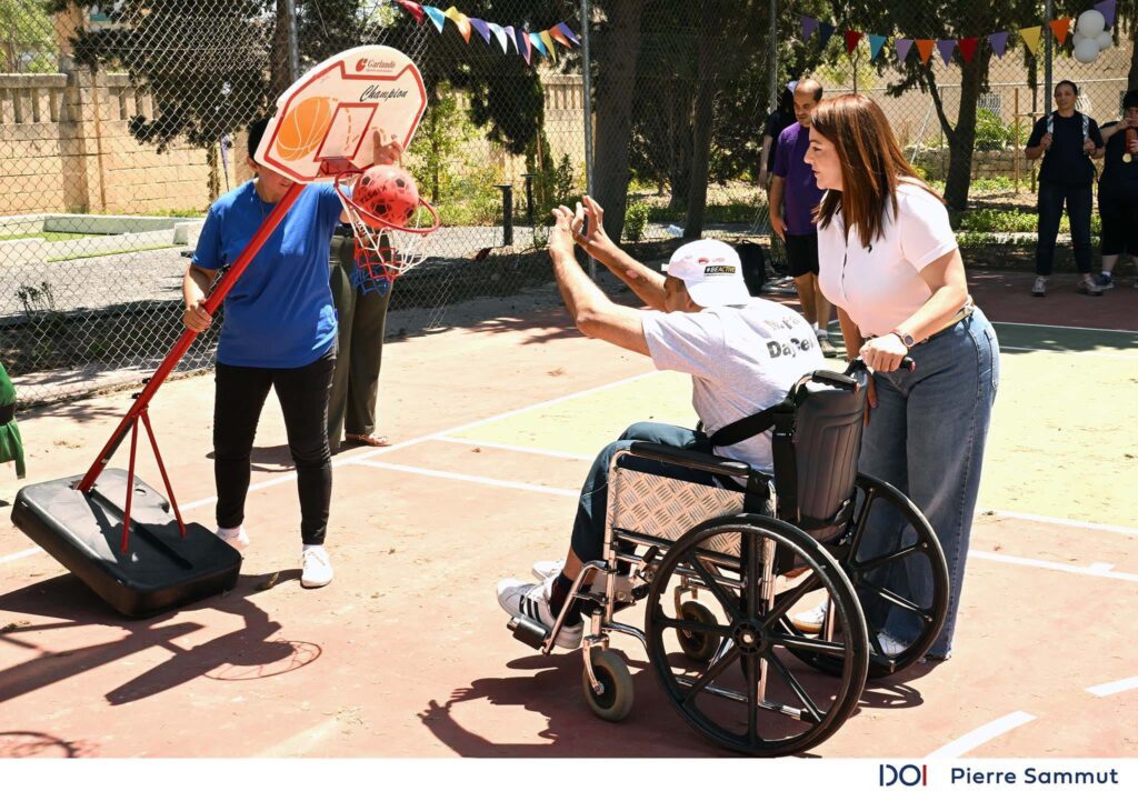 Il-Ministru Julia Farrugia ma' service user ġo siġġu tar-roti li qed jilgħab il-basketball
