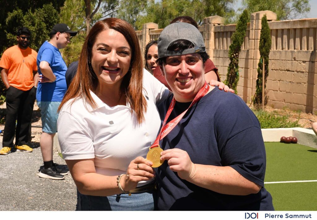 Il-Ministru Julia Farrugia ma' service user li qegħda żżomm medalja tad-deheb li rebħet fil-boċċe waqt il-UAE National Games 2026