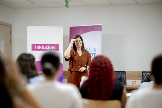 Ms Xuereb tidher fl-isfond tal-klassi, tagħmel is-sinjali, bil-lingwa tas-sinjali